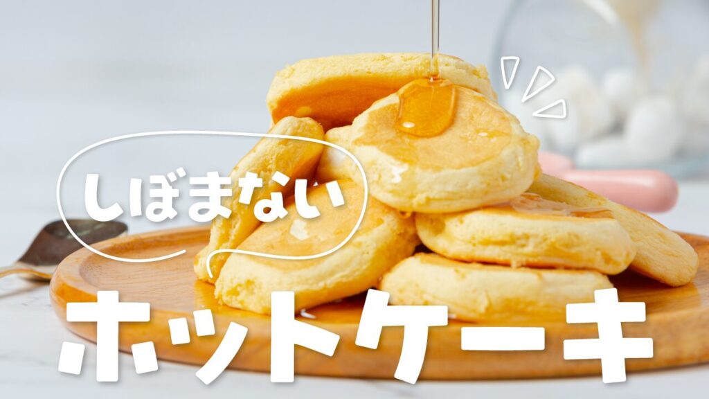 シロップがかけられている、木のお皿に盛られた分厚いホットケーキの写真に『しぼまない ホットケーキ』という文字を重ねた料理・レシピ系YouTubeサムネイルの作例。フリーフォントの『推しゴ』を使用しています。(サムネイルデザイナーおもち制作)